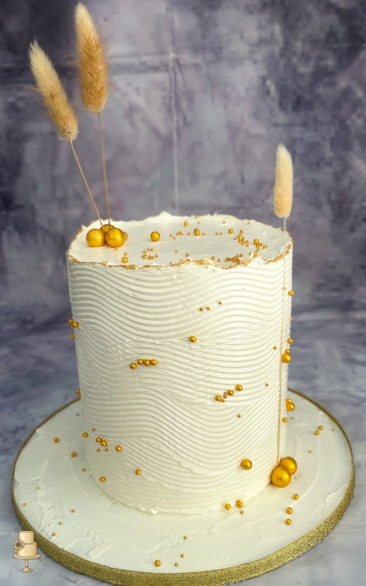 Buttercream wave cake with gold decorations and dried grass