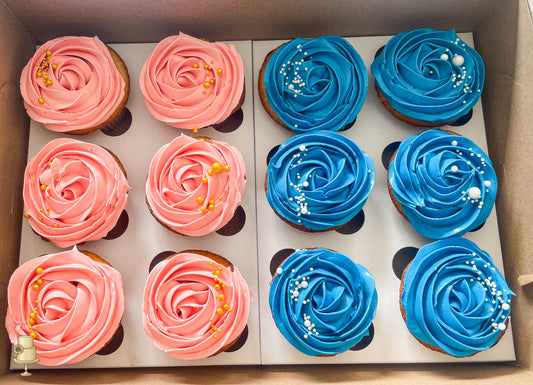 Box of cupcakes with pink and blue buttercream rosette frosting.